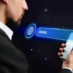Mężczyzna w garniturze trzyma smartfon, na którym wyświetla się pasek wyszukiwania z ikoną globu i tekstem "www...".
