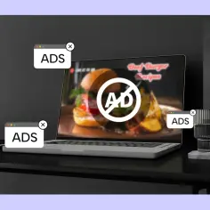 Laptop z zakrytą reklamą na ekranie, ikona Facebooka i okienka z napisem "ADS".